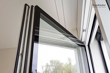 Vue détaillée d'une fenêtre bois/aluminium EgoSelectionPlus, vantail ouvert, verre à gradin visible