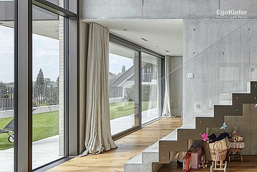 Vue intérieure d'une maison individuelle (villa) à Muri, portes coulissantes à levage EgoKiefer en bois/aluminium XL<sup>®</sup>2020 visibles