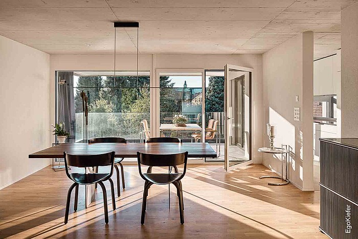 Vue intérieure d'une pièce d'habitation d'une maison à deux familles à Düdingen, porte de balcon ouverte