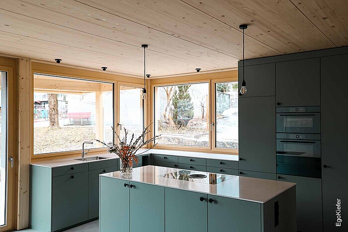 Cucina inondata di luce con finestre in legno naturale EgoWoodstar in una casa bifamiliare con vista sulla Torre Pulverturm