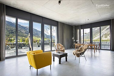Innenaufnahme Gewerbehaus Rossboden, Fensterfront mit Sicht nach aussen, gelber Sessel im Raum