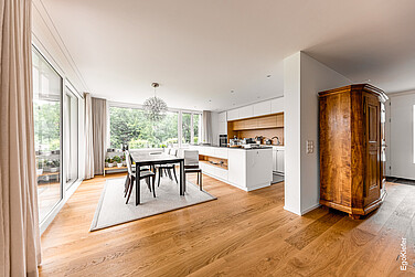 Innenaufnahme der Küche mit grossen Hebeschiebetüren und Holz/Aluminium-Fenstern mit Blick nach Draussen