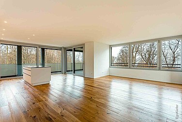 Innenaufnahme des Wohnzimmers/Küche mit grossen Holz/Aluminium-Fenstern und Hebeschiebetüren mit wunderschönem Blick nach Draussen