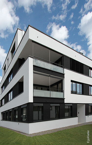 Aussenaufnahme Mehrfamilienhaus Seaside Bottighofen, weisse Fassade, dunkle Fenster