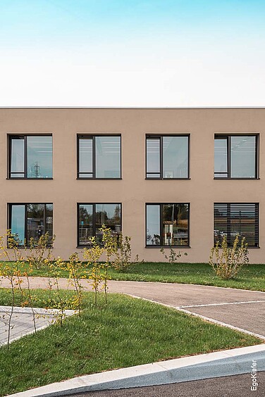 Aussenaufnahme, Frontansicht des Neubaus Schulhaus "Bellicot" in Echichens mit symmetrischen Fenstern.