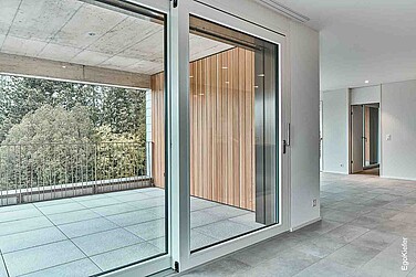 Innenaufnahme mit einer grossen Holz/Aluminium-Hebeschiebetüre links im Bild