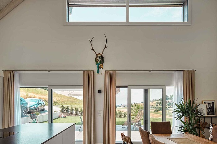 Vista interna della zona giorno del condominio di Alchenstorf, con grandi finestre e porte scorrevoli