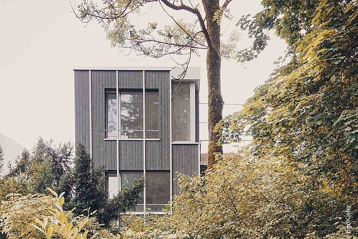 Vista esterna di una casa bifamiliare con finestre di grande formato e una suggestiva finestra ad angolo