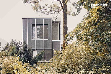 Vista esterna di una casa bifamiliare con finestre di grande formato e una suggestiva finestra ad angolo