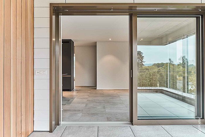 Aussenaufnahme einer Holz/Aluminium-Hebeschiebetüre offen einer Eingentumswohnung der Residence Lueg, Feldbrunnen