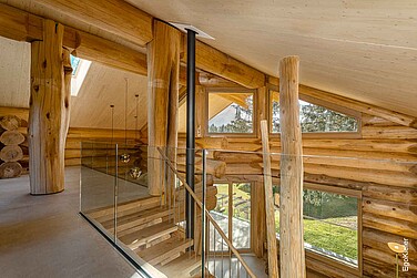 Innenaufnahme des oberen Stockwerks des Blockhauses in Amden/SG, mit mehreren Holzfenstern des Typs EgoWoodstar und einer eleganten Hebeschiebetür aus Holz, die perfekt in das architektonische Gesamtkonzept integriert sind.