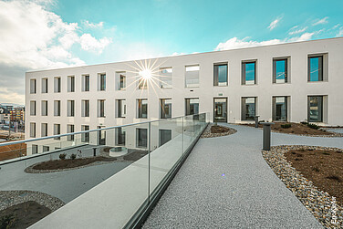 Aussenaufnahme des Gebäudes JED2226, eine ganze Front der EgoKiefer Holz/Aluminium-Fenstern EgoSelection mit intgierter Lüftungsklappe