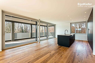 Vue intérieure d'un appartement dans le salon/cuisine avec une grande porte coulissante à levage en bois/aluminium et une fenêtre en bois/aluminium EgoAllstar