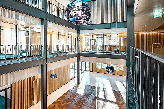 Vista interna della trasformazione della Banca Clientis Biene, con un grande atrio trasparente all'interno dell'edificio.