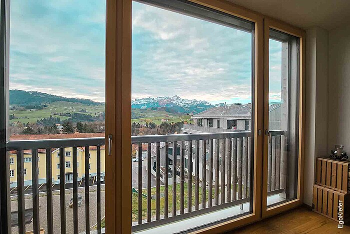 Vista interna di un appartamento nell'edificio Ochsenwies Waldstatt con una porta scorrevole che offre una fantastica vista sulle montagne dell'Alpstein.