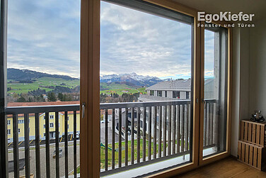 Vista interna di un appartamento nell'edificio Ochsenwies Waldstatt con una porta scorrevole che offre una fantastica vista sulle montagne dell'Alpstein.
