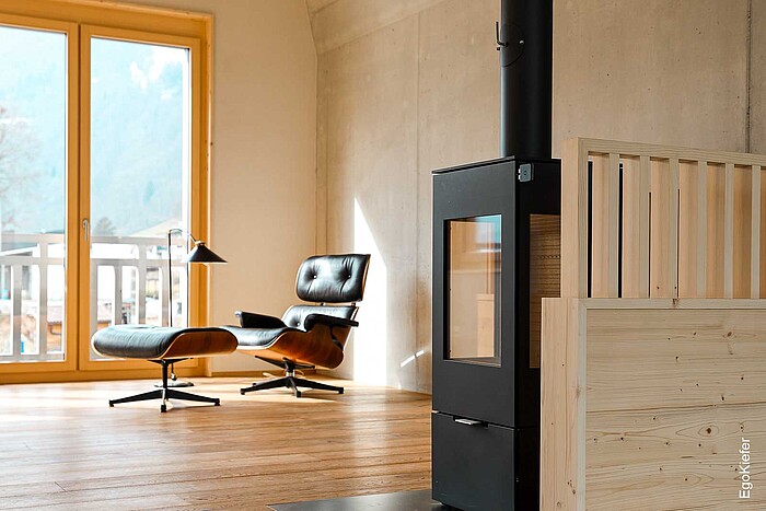 Soggiorno della casa bifamiliare con vista sulla torre Poudrière con finestre in legno, Eames Lounge Chair e stufa a legna