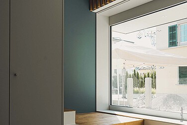 Innenaufnahme mit einem grossen Holz/Aluminium-Fenster EgoAllstar mit einem schönen Blick nach Draussen