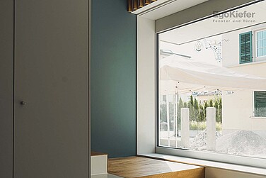 Innenaufnahme mit einem grossen Holz/Aluminium-Fenster EgoAllstar mit einem schönen Blick nach Draussen
