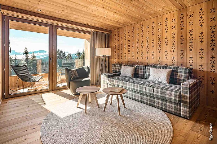 Intérieur d'une chambre du Tgiasa Principala dans un nouveau look, avec des fenêtres en bois EgoKiefer qui offrent une belle vue sur l'extérieur