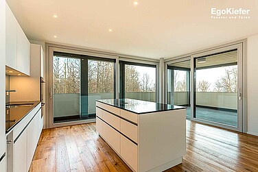 Innenaufnahme einer Wohnung des Wohnblocks Seemoosholz in Arbon, Bild in der Küche mit zwei grossen Hebeschiebetüren aus Holz/Aluminium