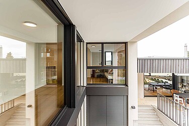 Moderne Fensterfront mit Blick auf Terrasse, Treppe und Innenraum. Links im Bild ein grosses Fenster, welches festverglast ist