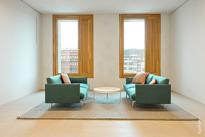 Foto dell'interno con due finestre EgoKiefer identiche in legno/alluminio EgoSelection, a destra si vede lo sportello di ventilazione integrato.