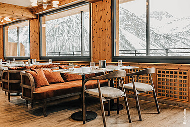Innenaufnahme im Restaurant des Alpenresorts FAERN in Arosa, mit wunderschönem Ausblick auf die Winterlandschaft, dank grossen EgoKiefer Holz/Aluminium-Fenstern
