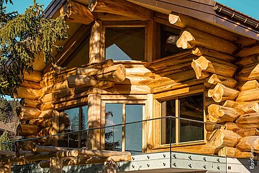 Detailansicht eines Blockhauses in Amden, Schweiz, mit massiver Holzbauweise und Holzfenstern des Typs EgoWoodstar, die sich harmonisch in die rustikale Architektur einfügen.