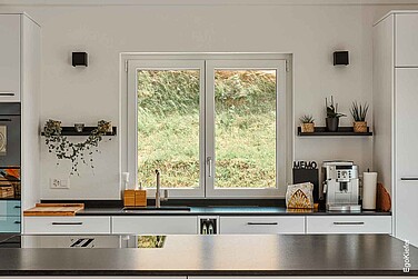 Innenaufnahme aus der Küche des MFH in Alchenstorf, von der aus der Bilck durchs Fenster ins Grüne führt