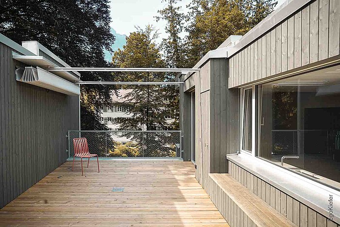 Vista esterna, terrazza sul tetto con vista unica sulle corone degli edifici e a sinistra con le finestre in legno/alluminio EgoAllstar di EgoKiefer