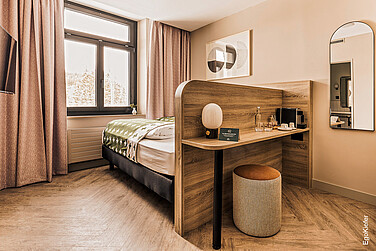Innenaufnahme eines hellen Zimmers, dank EgoKiefer Holz/Aluminium-Fenster. Der Blick nach Draussen kann direkt vom Bett aus genossen werden.
