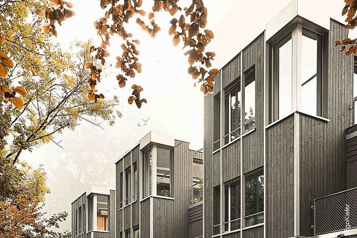 Foto esterna delle quattro moderne case a schiera con grandi finestre in legno/alluminio EgoKiefer "EgoAllstar" e una suggestiva finestra ad angolo