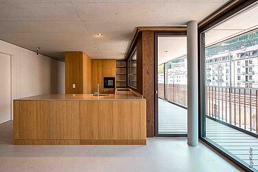 Hochwertige Innenansicht einer Wohnung in der Überbauung Reussinsel 3 in Luzern. Offene Küche mit Holzverkleidung, geschosshohe Glasfront, EgoKiefer Holz/Aluminium-Fenster EgoAllstar und EgoSelection wurden bei diesem Objekt eingebaut