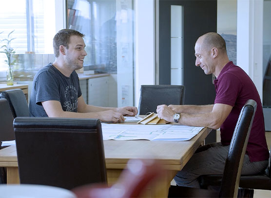 Deux hommes s'assoient à la table et se parlent.