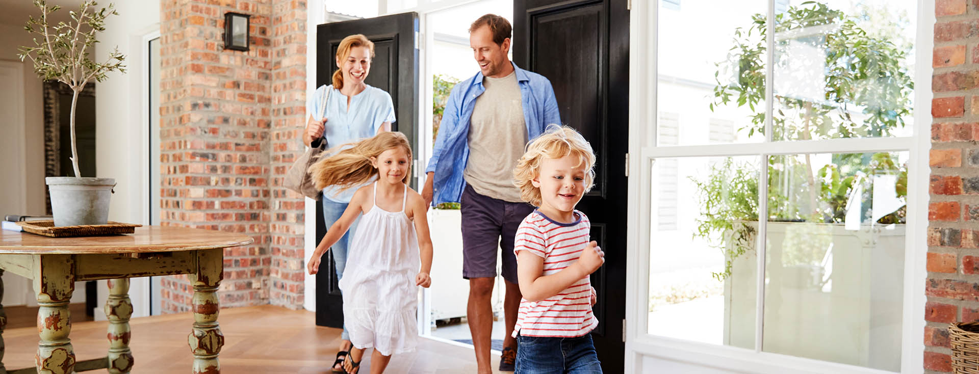 Familie betritt ein helles Wohnzimmer durch eine geöffnete Tür