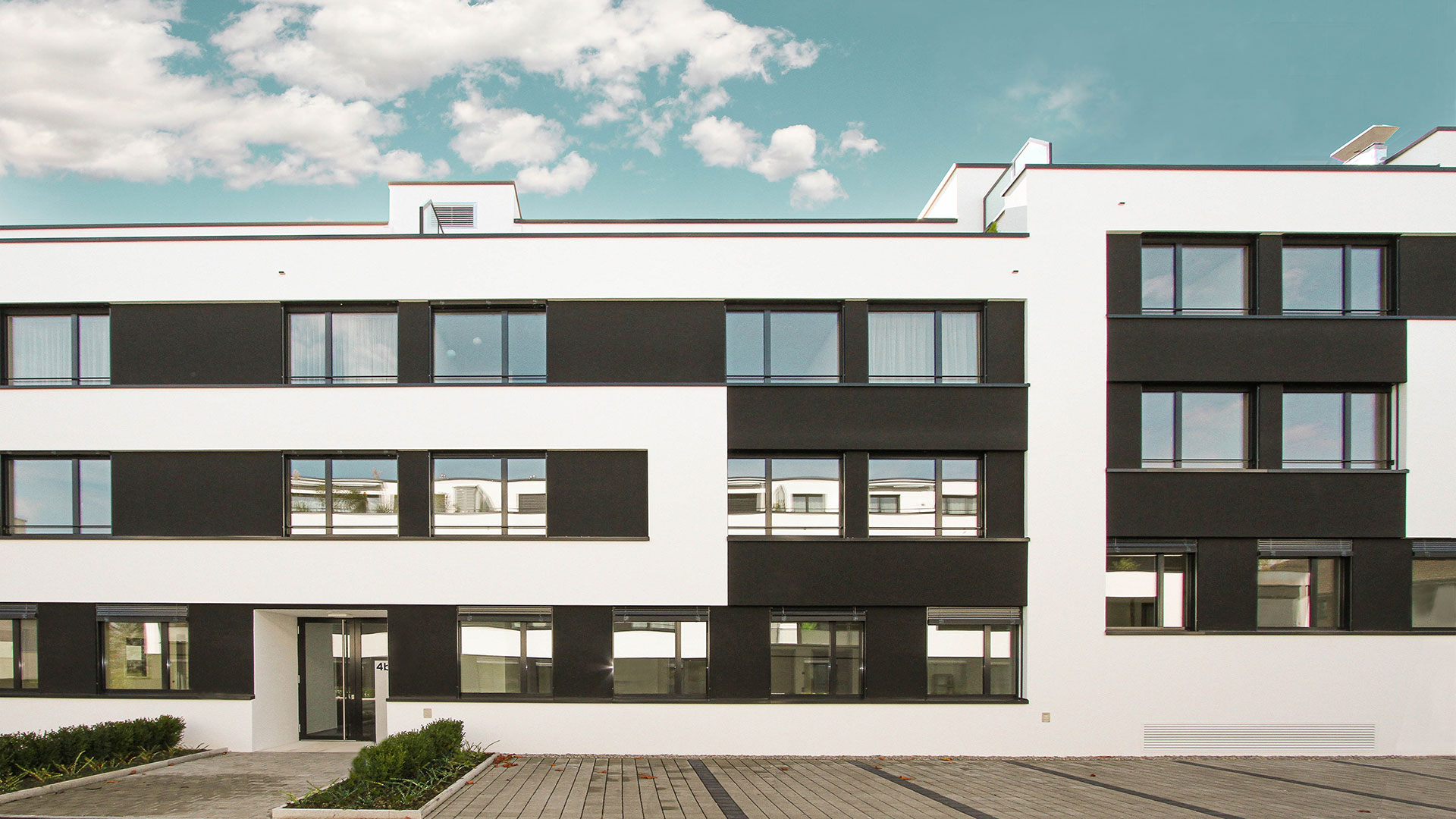 Aussenaufnahme Mehrfamilienhaus Seaside Bottighofen, weisse Fassade, dunkle Fenster